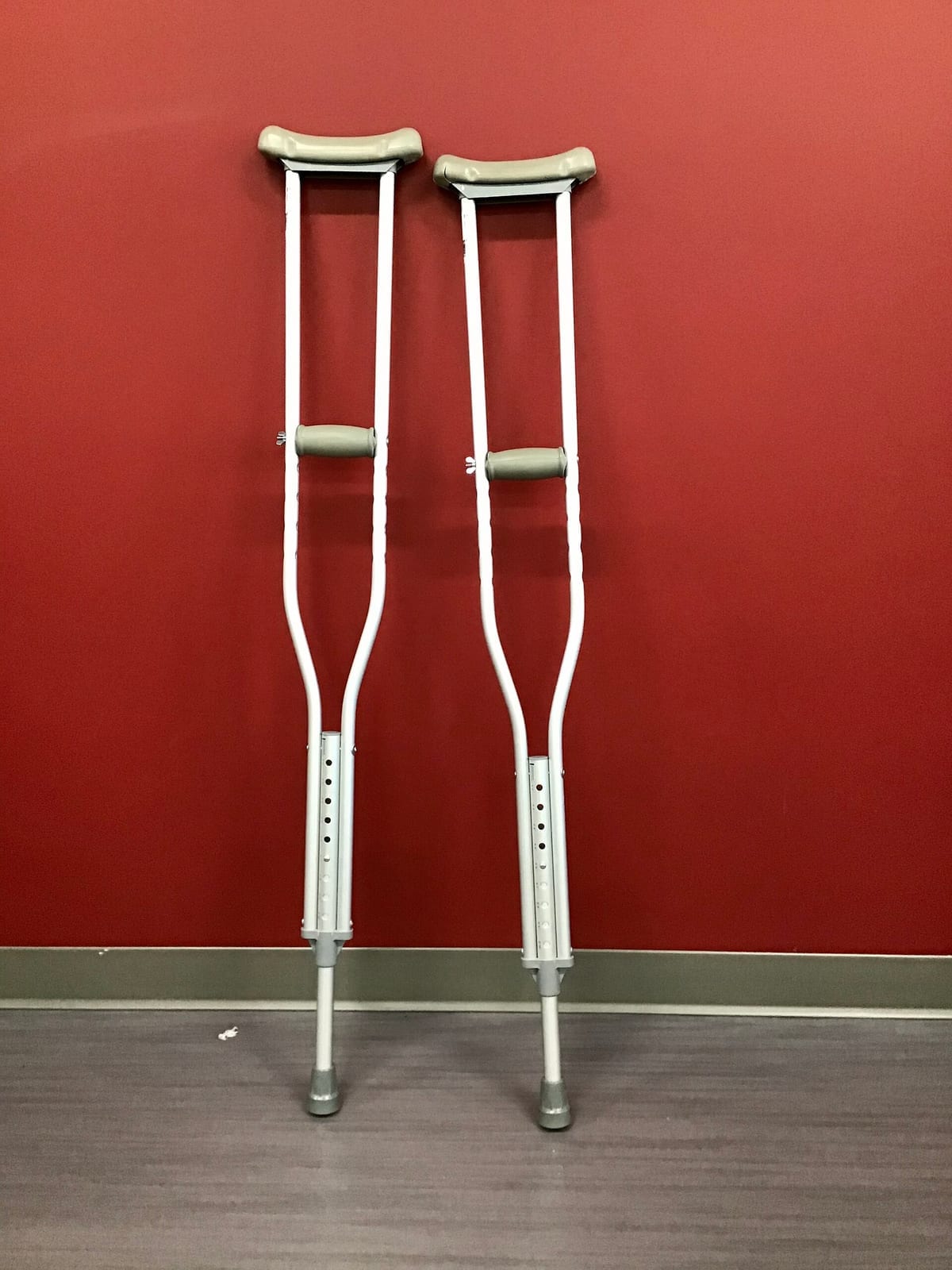 Par de muletas encostado numa parede vermelha