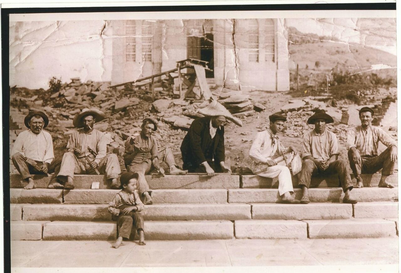 Operários sentados nos degraus de uma obra, em foto antiga